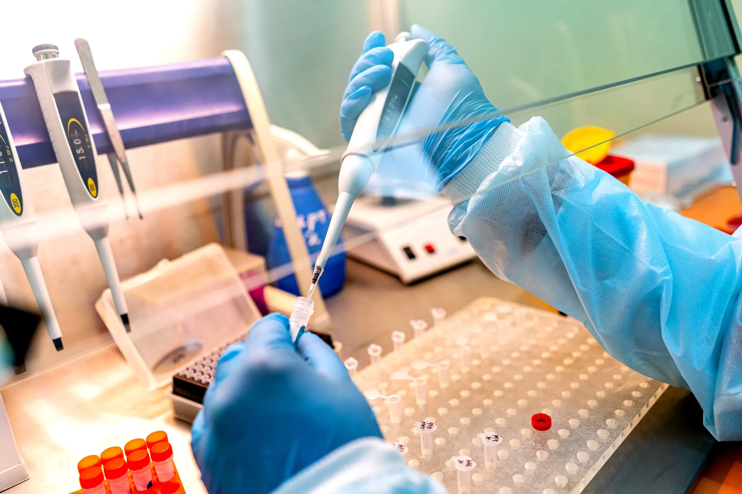Gloved hands pipetting a sample in a laboratory biosafety cabinet — illustrative of analytical bench work, not a specific FabUTech assay.