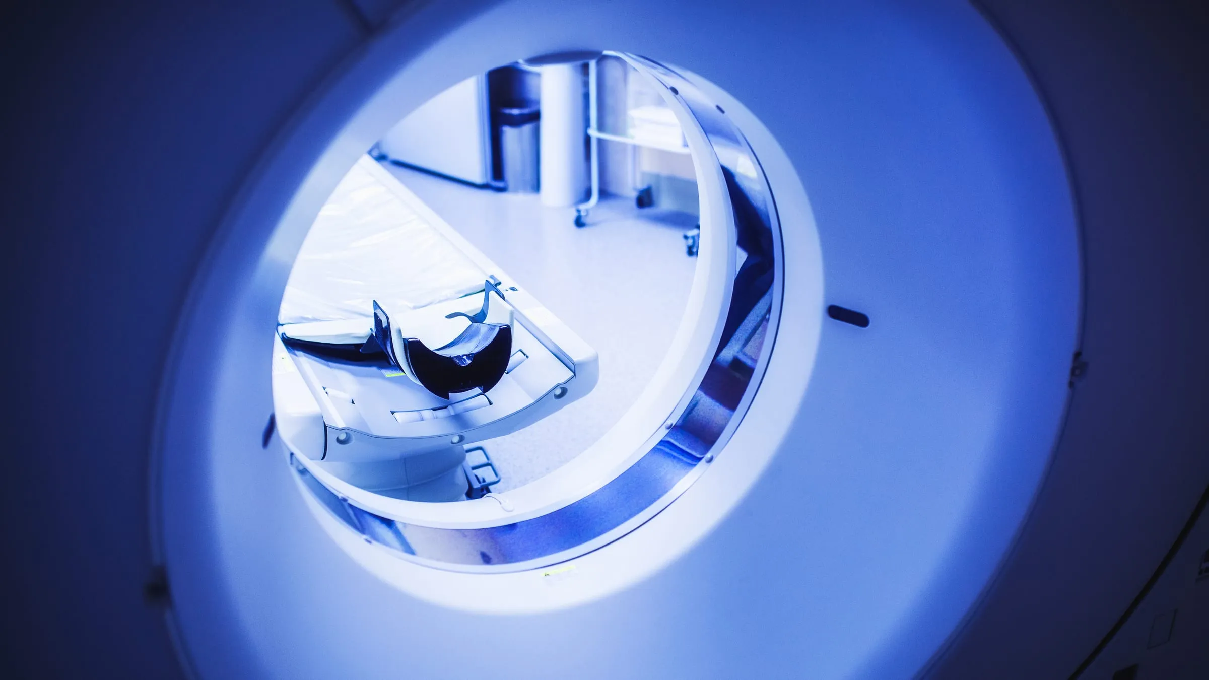 Looking into the softly lit bore of a PET/CT scanner in a nuclear-medicine imaging suite.